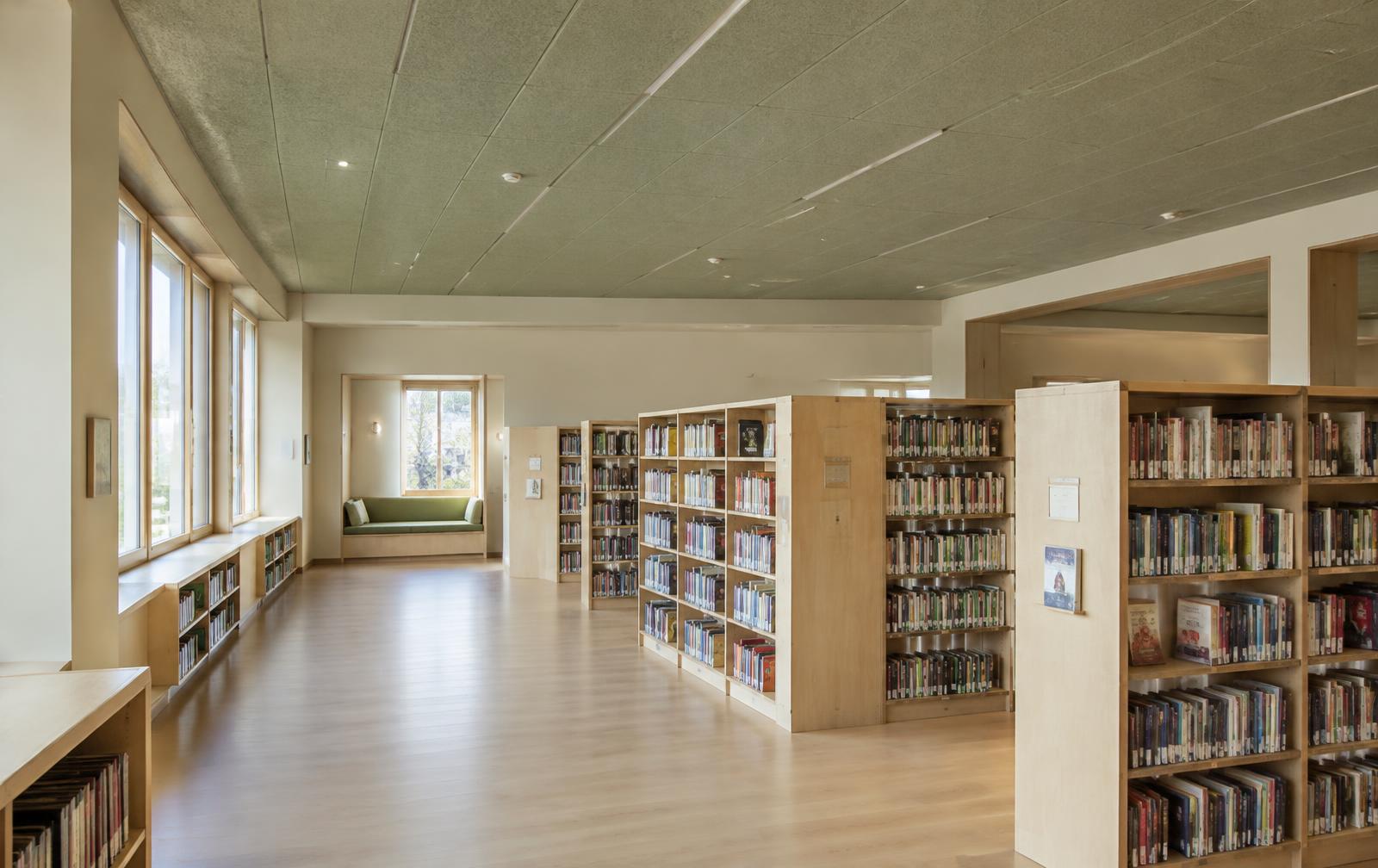 Placeholder image: an empty school reading room with pale timber floors, sage acoustic ceiling panels, soft north daylight and a quiet built-in bench alcove.